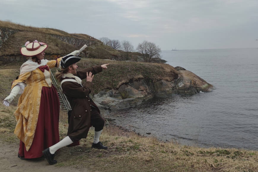 historialliseen tyyliin pukeutuneet henkilöt katsovat merelle